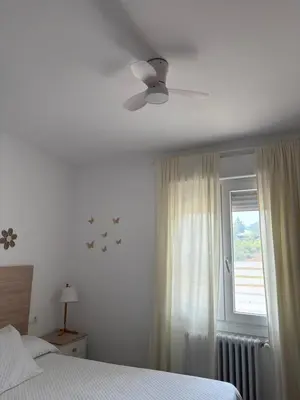 a white bedroom with a bed and a window at El pisito de Cris y Mia in Ponferrada