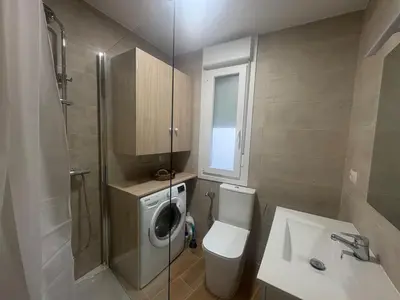 a bathroom with a toilet and a sink and a washing machine at El pisito de Cris y Mia in Ponferrada