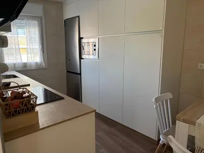 a kitchen with a refrigerator and a table with a chair at El pisito de la Estrella in Ponferrada