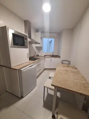a kitchen with white appliances and a table with chairs at Apartamento Centro Calle Reina in Lugo
