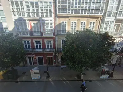 a man riding a skateboard down a street in front of buildings at Apartamento Centro Calle Reina in Lugo