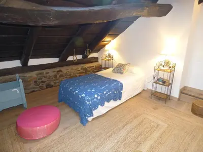 a bedroom with a bed with a blue blanket and a stool at Luna Creciente Casa Luna de La Viliella in La Viliella