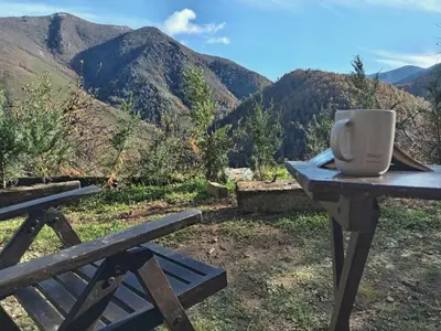 a cup on a picnic table with a view of mountains at Luna Creciente Casa Luna de La Viliella in La Viliella