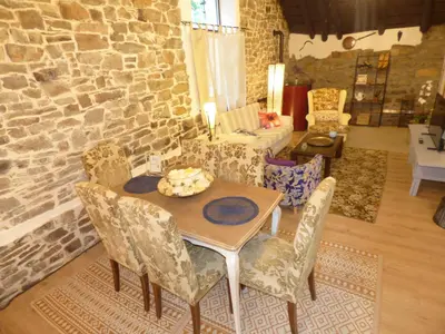 a table and chairs in a room with a stone wall at Luna Creciente Casa Luna de La Viliella in La Viliella