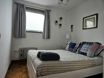 a bedroom with a bed with blue pillows and a window at Manzaneda Natura T1 in Puebla de Trives