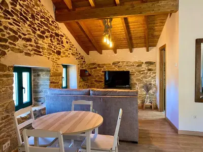 a dining room with a table and chairs and a stone wall at Casa Veracruz Sanabria in Puebla de Sanabria