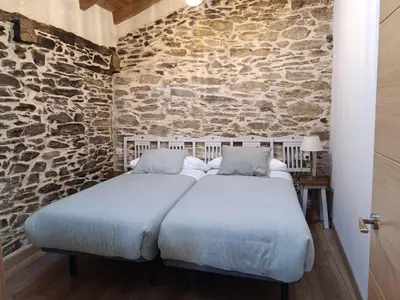 two beds in a room with a stone wall at Casa Veracruz Sanabria in Puebla de Sanabria