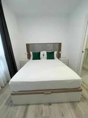 a bed with white sheets and green pillows at Paseo Malecón Hab in Monforte de Lemos