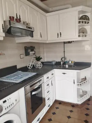 a kitchen with white cabinets and a sink and a dishwasher at Casa Belén in Burela de Cabo