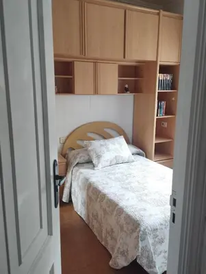 a bedroom with a bed and wooden cabinets at Casa Belén in Burela de Cabo