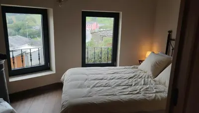 a bedroom with two large windows and a bed at La casa de las ovejas