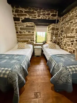 two beds in a room with a stone wall at Meson el Acebo in El Acebo de San Miguel
