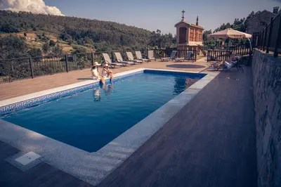 two people standing in a swimming pool at Casa Rural A Avoa María in Campo Lameiro