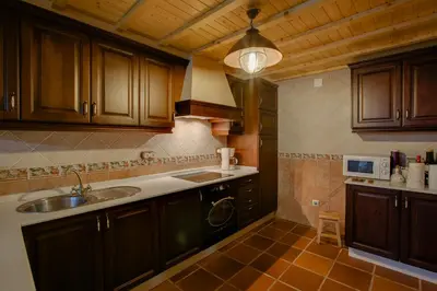 a kitchen with wooden cabinets and a sink at Casa Rural A Avoa María in Campo Lameiro