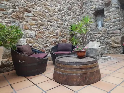 two chairs and a table in front of a stone wall at Casa Rural A Avoa María in Campo Lameiro