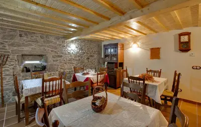 a dining room with two tables and a stone wall at Casa Rural A Avoa María in Campo Lameiro