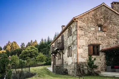 an old stone house with a balcony and trees at Casa Rural A Avoa María in Campo Lameiro