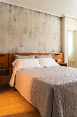 a bedroom with a large bed with a wooden headboard at Motel Venecia in Taboadela