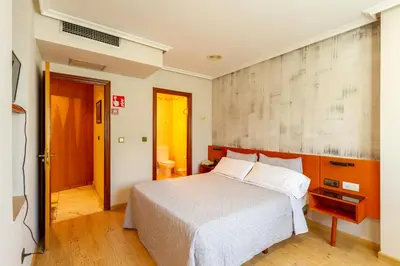 a bedroom with a white bed and a wall at Motel Venecia in Taboadela