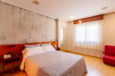 a bedroom with a bed and a red chair at Motel Venecia in Taboadela