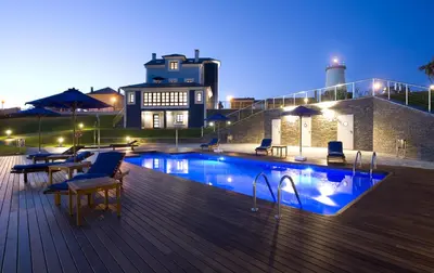 a pool on a deck with chairs and a building at Apartamentos Viavelez in La Caridad