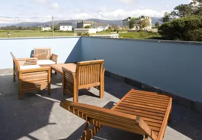 two wooden chairs and a table on a roof at Apartamentos Viavelez in La Caridad