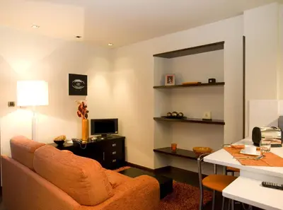 a living room with an orange couch and a desk at Apartamentos Viavelez in La Caridad