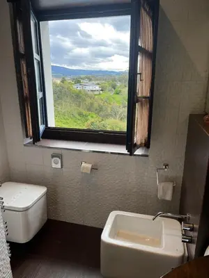 a bathroom with a window and a toilet and a sink at Apartamentos Viavelez in La Caridad