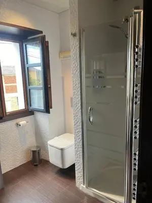 a bathroom with a toilet and a glass shower at Apartamentos Viavelez in La Caridad