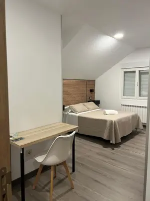 a bedroom with two beds and a desk with a chair at Pensión Ferreiriño in Quiroga
