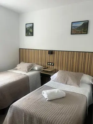 a hotel room with two beds and a desk at Pensión Ferreiriño in Quiroga