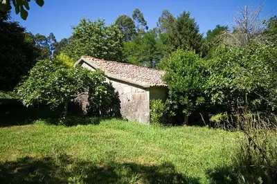 an old stone building in a field with trees at Pazo do Vilar in Padrón