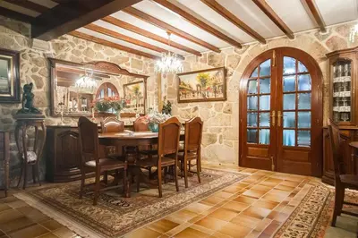 a dining room with a table and a stone wall at Pazo do Vilar in Padrón