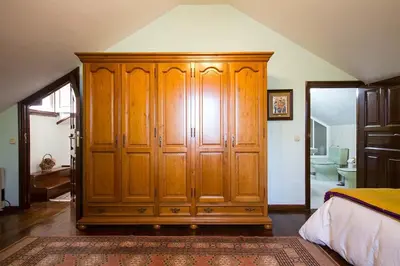 a large wooden cabinet in a bedroom with a bathroom at Pazo do Vilar in Padrón