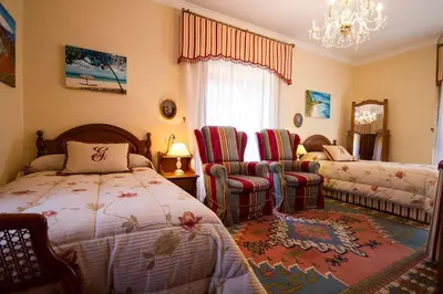 a bedroom with a bed and two chairs and a chandelier at Pazo do Vilar in Padrón