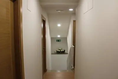 a hallway with white walls and a stairway with flowers at Pensión CasaBlanca in Arzúa