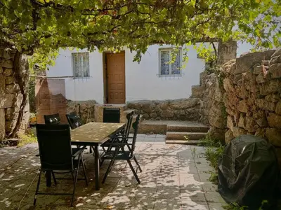 a table and chairs sitting under a stone wall at Casa con parra de uva y paz
