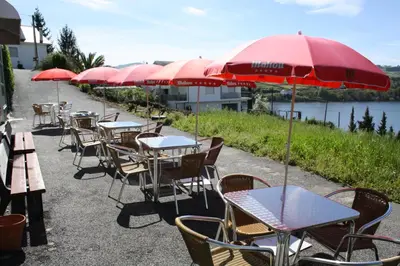 a row of tables and chairs with red umbrellas at Albergue Ferramenteiro in Portomarin
