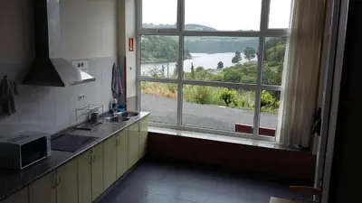 a kitchen with a large window looking out at a view at Albergue Ferramenteiro in Portomarin