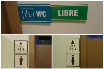 a sign for a restroom with a sign for a toilet and a sign for at Albergue Ferramenteiro in Portomarin