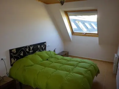 a green bed in a room with a window at Ático a 5 minutos de TODO Mariña Lucense in Viveiro