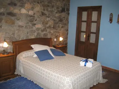 a bedroom with a bed and a stone wall at Casa Pipa in Pola de Somiedo