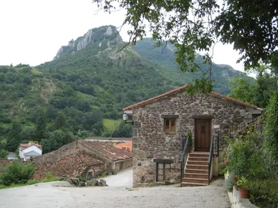 a stone house with a mountain in the background at Casa Pipa in Pola de Somiedo
