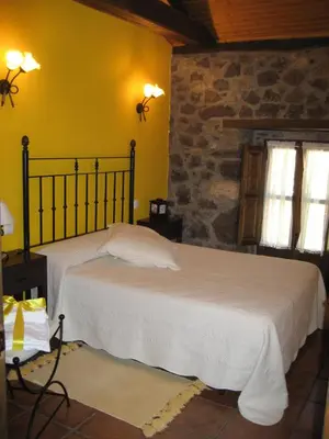 a bedroom with two beds and a stone wall at Casa Pipa in Pola de Somiedo