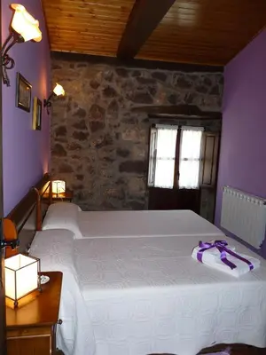 a bedroom with a large white bed with purple walls at Casa Pipa in Pola de Somiedo