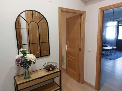 a room with a vase of flowers on a table with a mirror at Apartamento Puerta de San Fernando in Lugo
