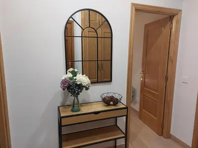 a vase of flowers on a table with a mirror at Apartamento Puerta de San Fernando in Lugo