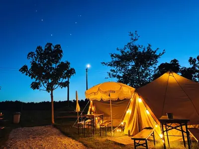 two tents with chairs and a table at night at O Pedrouzo Pilgrim Camp in O Pedrouzo