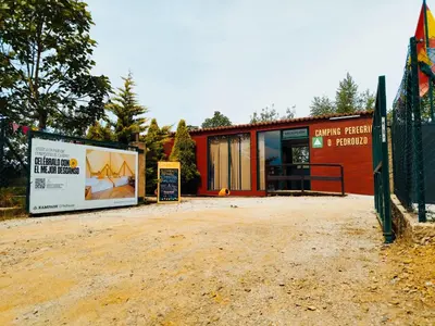 a red building with a sign in front of it at O Pedrouzo Pilgrim Camp in O Pedrouzo