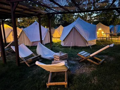a group of tents in the grass with chairs and tables at O Pedrouzo Pilgrim Camp in O Pedrouzo